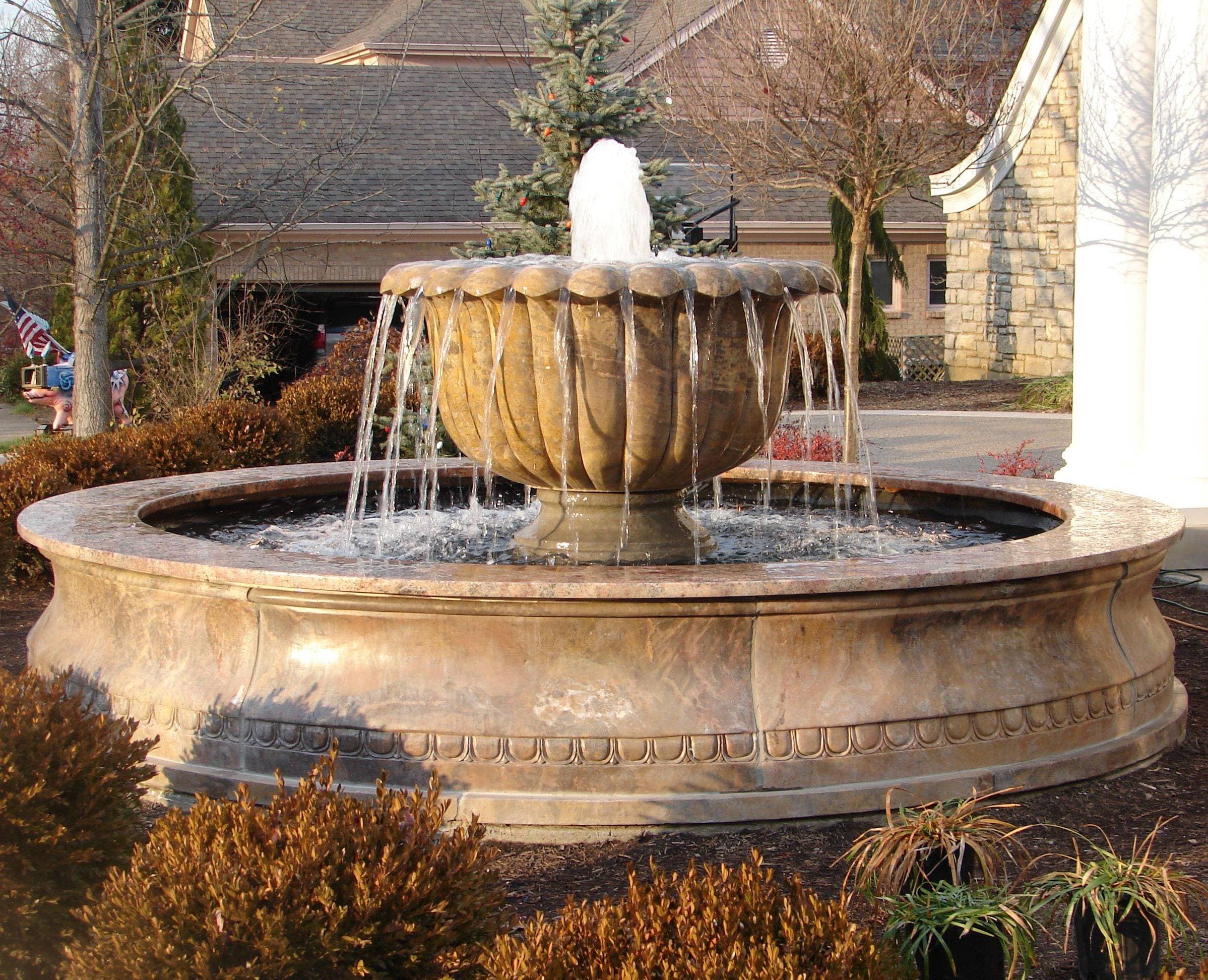 Underwater lights and a pump laid out beside a stone fountain basin