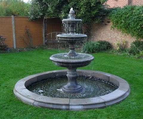 A tiered fountain set within a circular stone pool surround
