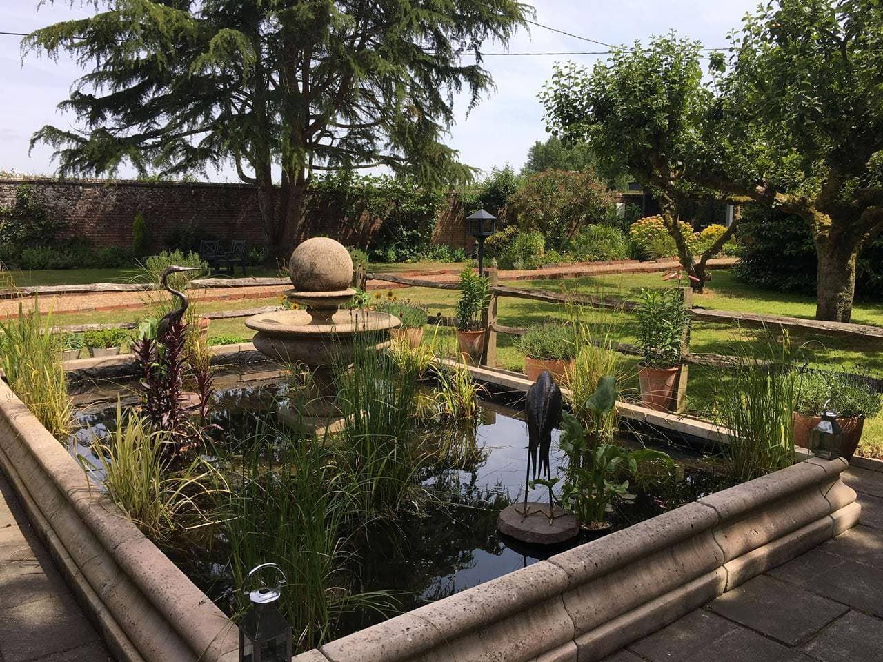 A tiered stone fountain installed in a customer's garden, showing its scale against the house